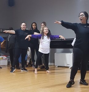 Miss Chiara leading a dance class. Students are happily following her along..