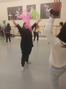 Girl happy dancing with pink and green scarfs