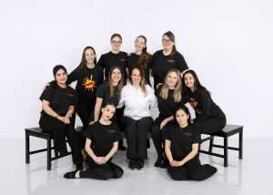 11 Female team members wearing black dance ability tshirts pose for the camera grouped together